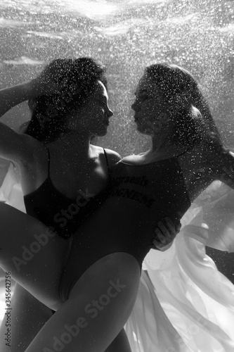 Two beautiful lesbian girls are swimming underwater. Attractiveness. Sexual poses and gestures. Female dance underwater. Swimwear and pool. Two mermaids. Two girlfriends women.Gay girls. Same-sex love