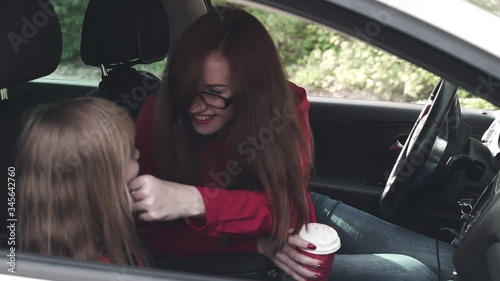Family in the car. Mom and little girl daughter together in the car rejoice and dance to the music. Slow motion