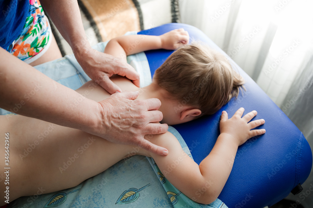 Doctor osteopath massage therapist is doing massage to a little boy. Hands massage the back and cervical-collar zone. Mom gives her baby a massage. Doctor osteopath massage therapist is doing massage to a little boy. Hands massage the back and cervical-collar zone. Mom gives her baby a massage.