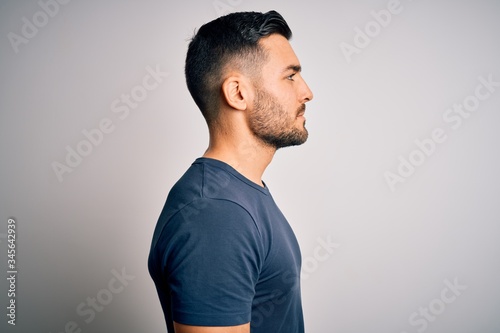 Young handsome man wearing casual t-shirt standing over isolated white background looking to side, relax profile pose with natural face with confident smile. photo