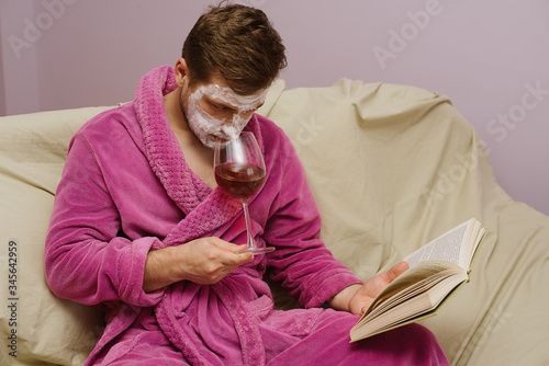 Man have spa cosmetic mask, wine and read book at home during the corona crisis at home isolation. Coronavirus quarantined.