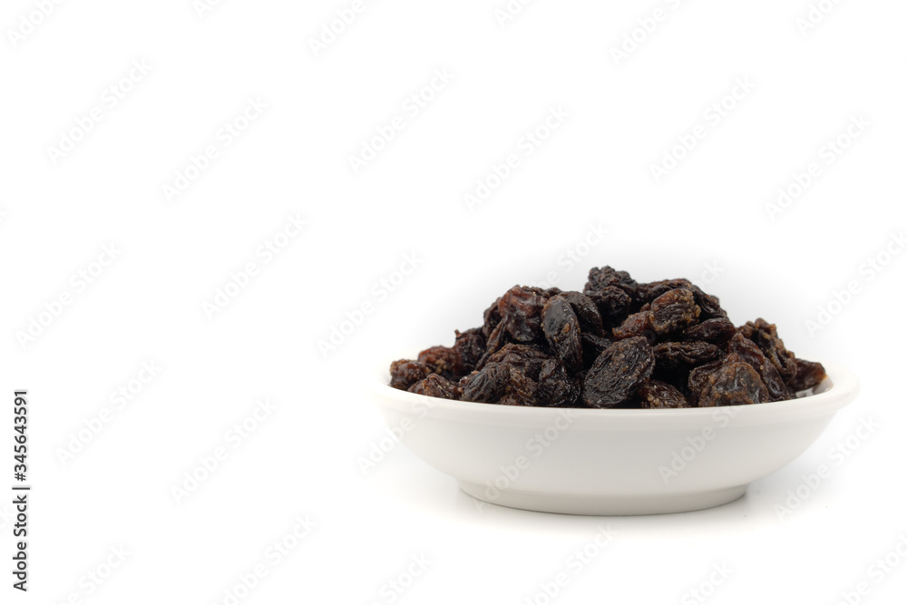 Dried black raisin in white bowl isolated in white background. Dried black raisin in white bowl isolated in white background.