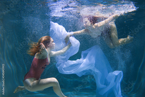 Two beautiful lesbian girls are swimming underwater. Attractiveness. Sexual poses and gestures. Female dance underwater. Swimwear and pool. Two mermaids. Two girlfriends women.Gay girls. Same-sex love