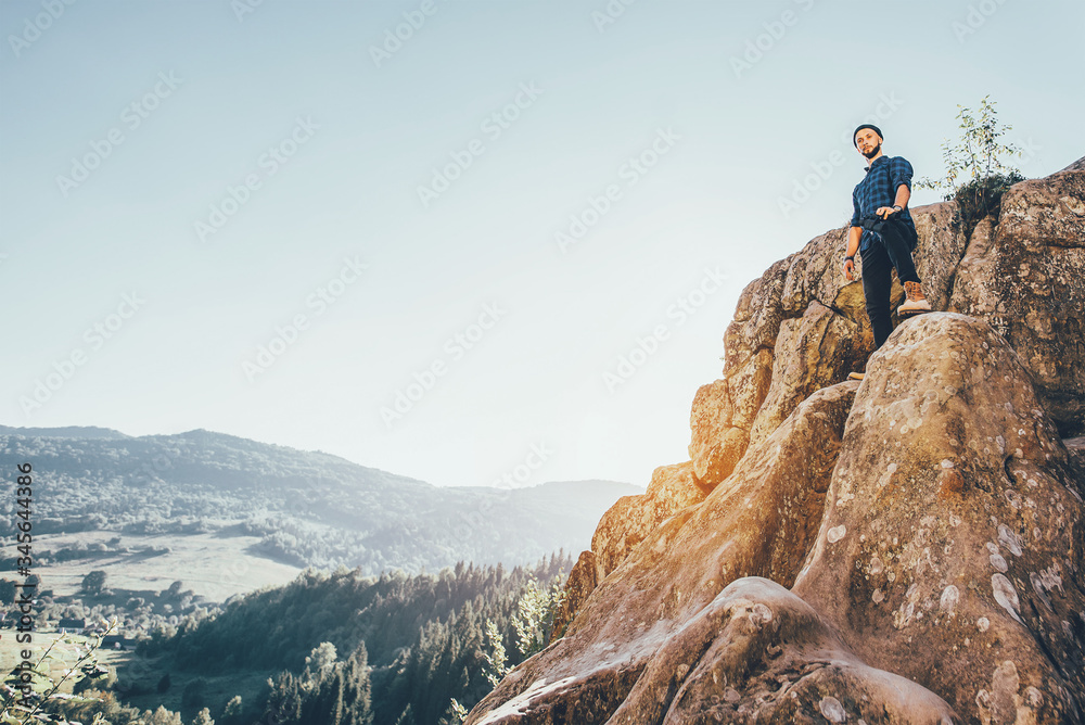 A traveler man with big backpack standing on the rocks and looking forward. Toned photo