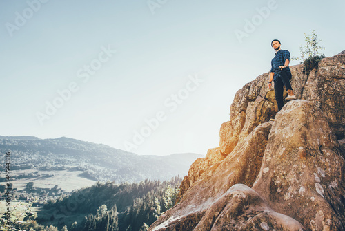 A traveler man with big backpack standing on the rocks and looking forward. Toned photo