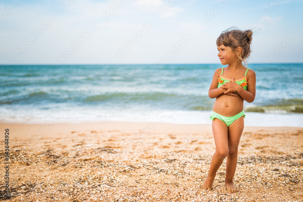 Joyful little girl enjoys a beach day while relaxing at sea on a sunny warm summer day. Summer vacation and relaxation concept Joyful little girl enjoys a beach day while relaxing at sea on a sunny warm summer day. Summer vacation and relaxation concept