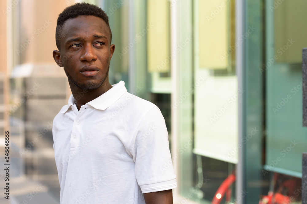 Portrait of young African man thinking and looking back in the city outdoors Portrait of young African man thinking and looking back in the city outdoors