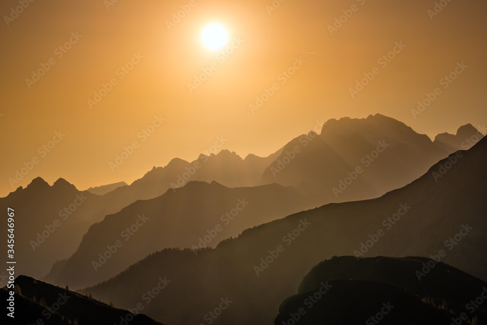 Sun glow in evening hazy sky and mountain silhouettes view