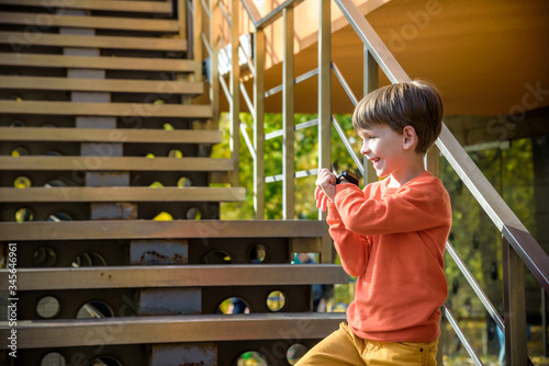 Photo of the boy looking at a smart watch. Children and modern technology. Kid calling to his friends or parents after school