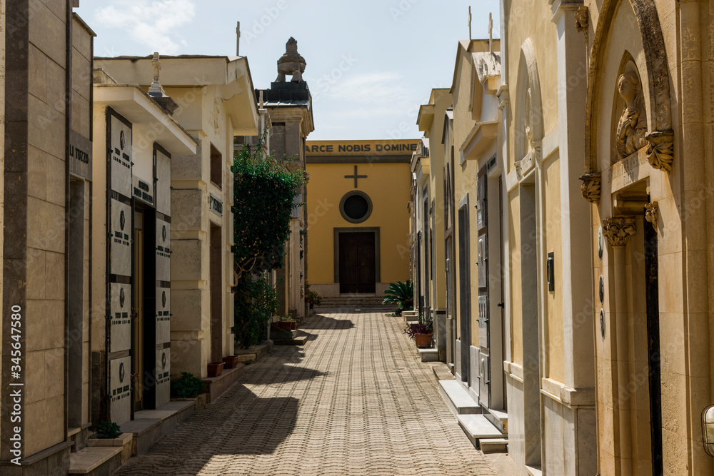 Obraz premium Balestrate, Sicily, Italy - 09/18/2018: Interesting photo presenting Italian, Christian cemetery, shot in Balestrate, near Palermo. Alley with tombs on the sides. Each building for one family. 