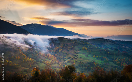 Bright colorful sunrise in mountains with smoke and dramatic bright sky