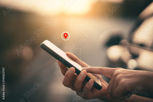 Woman hand using smart phone with navigator location point at street background. Technology interenet and travel adventure concept. photo