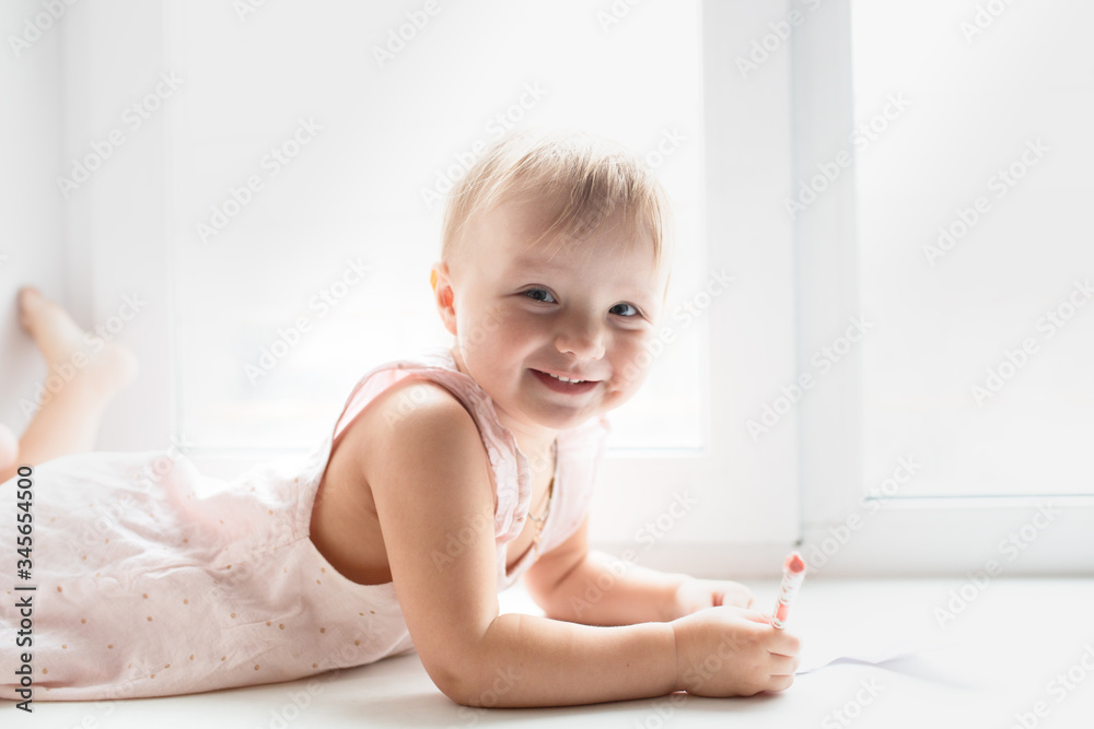 Caucasian baby girl lies and paints on windowsill Caucasian baby girl lies and paints on windowsill