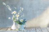spring flowers in vases on background old wall