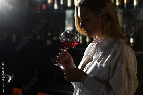 Photography Blonde young pretty girl sommelier holding and smelling a glass of red wine