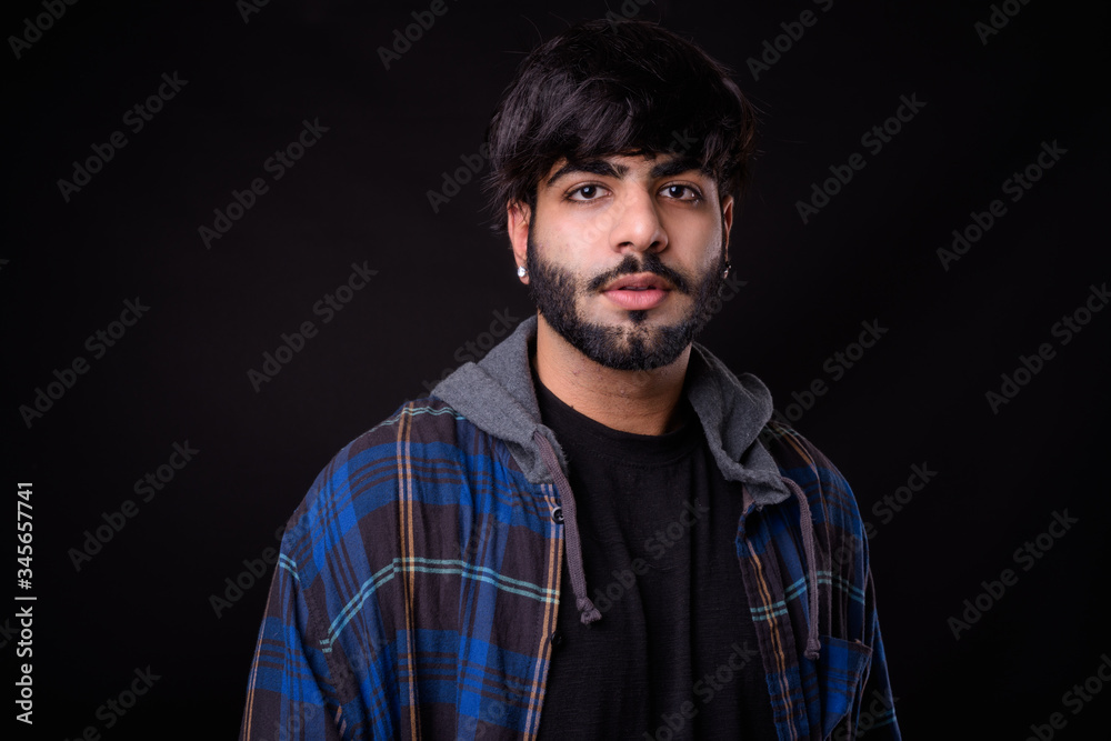 Portrait of young handsome bearded Indian hipster man