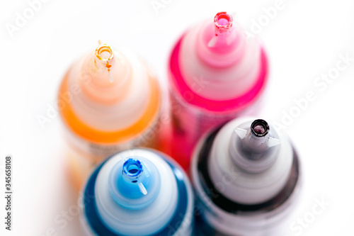 Four open printer bottles with CMYK colour ink.