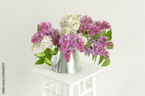 Bouquet of lilac in tin jug on stand indoor. Minimal and Scandinavian style