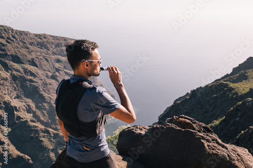 Portrait of young man drinking energy sports nutrition energy gel while sitting and resting after trail running