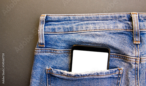 White screen smartphone in jeans pocket. Smartphone place for text. Smartphone in a pocket on a black background.  Copy Space