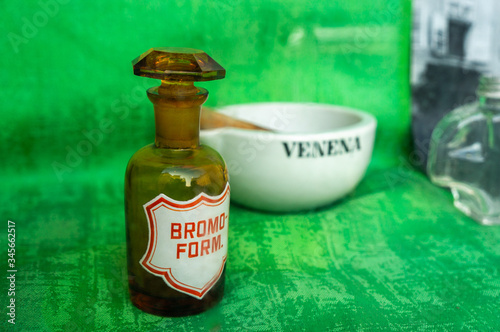 Vintage Victorian glass medicine bottles and jars in a chemist display in macro on deep green background photo