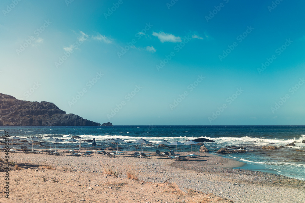 Parasols and empty sun beds on a stone beach Parasols and empty sun beds on a stone beach