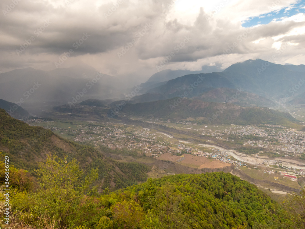 A scenic, aerial view of dark clouds hanging over the valley below the Himalayan village of Sarangkot near Pokhara in Nepal.