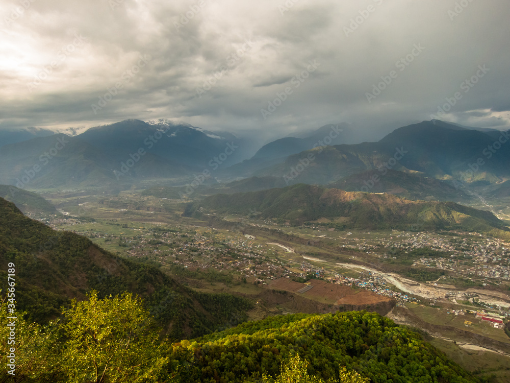 A scenic, aerial view of dark clouds hanging over the valley below the Himalayan village of Sarangkot near Pokhara in Nepal.