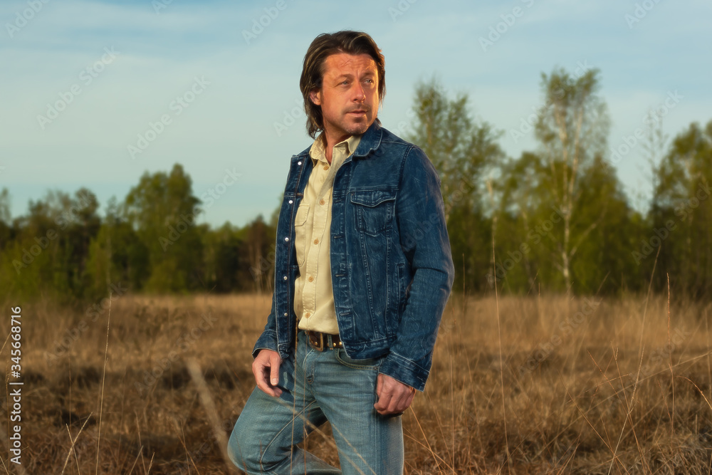 Man in jeans jacket and shirt in nature reserve at sunrise during spring. Man in jeans jacket and shirt in nature reserve at sunrise during spring.
