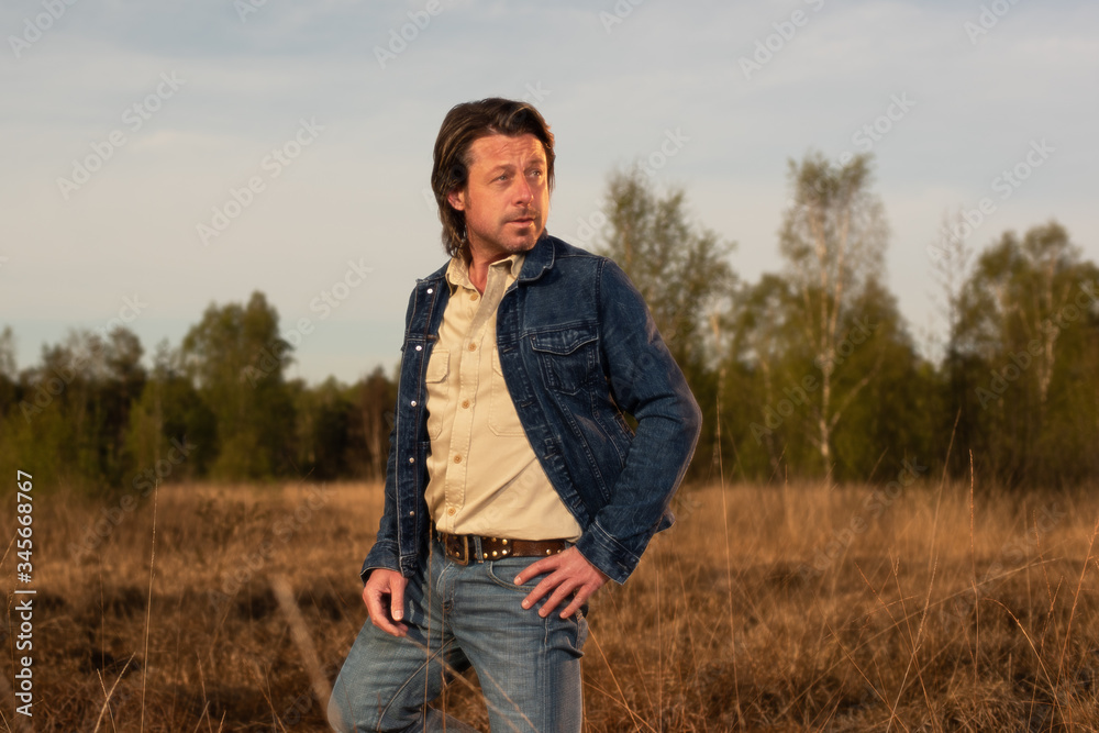 Man in jeans jacket and shirt in nature reserve at sunrise during spring. Man in jeans jacket and shirt in nature reserve at sunrise during spring.