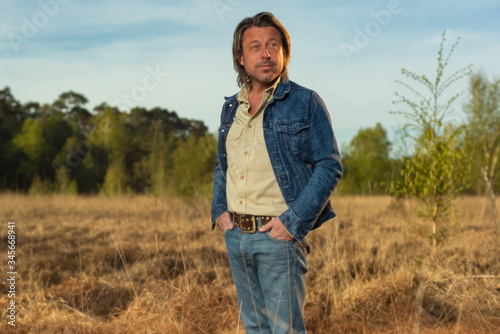 Man in jeans jacket and shirt in nature reserve at sunrise during spring. © ysbrandcosijn