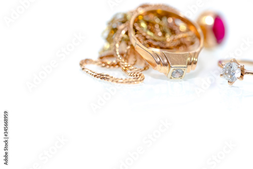 Real gold rings, diamonds , gems on white shiny surface close up macro shot.