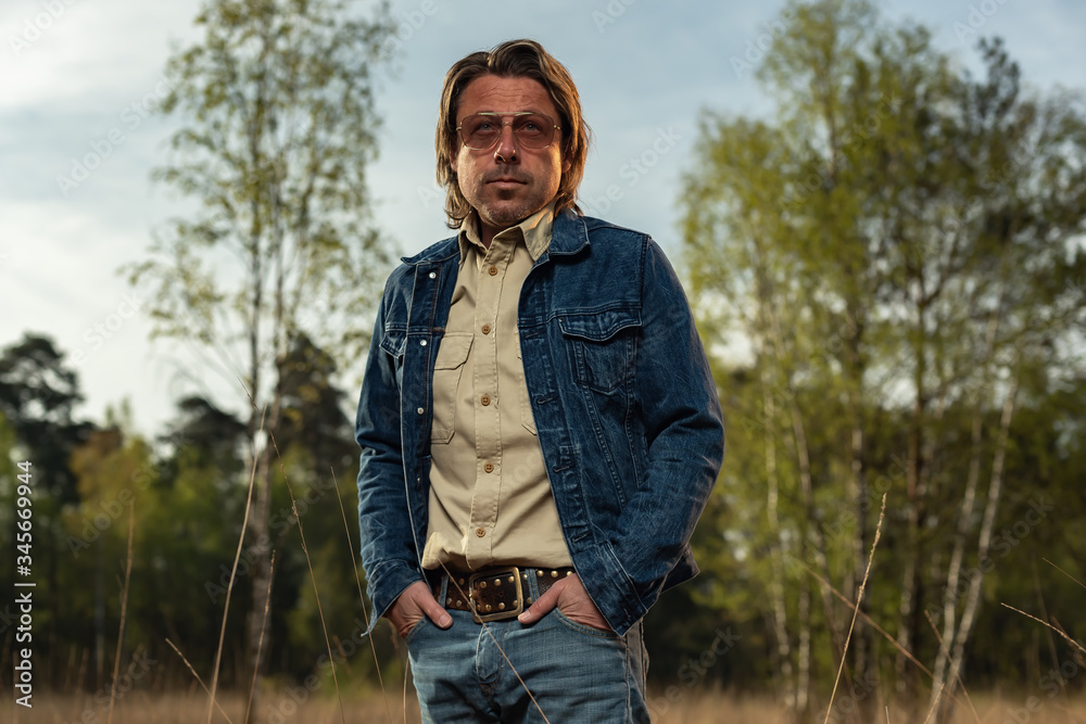 Man with sunglasses in denim jacket in nature reserve at sunrise during spring. Man with sunglasses in denim jacket in nature reserve at sunrise during spring.