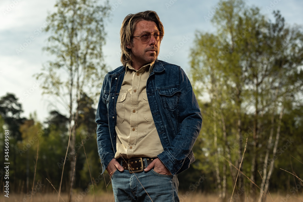 Man with sunglasses in denim jacket in nature reserve at sunrise during spring. Man with sunglasses in denim jacket in nature reserve at sunrise during spring.