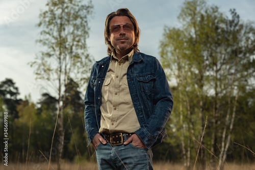 Man with sunglasses in denim jacket in nature reserve at sunrise during spring. © ysbrandcosijn