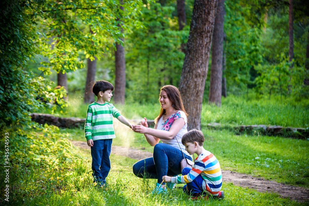Φωτογραφία Young woman mother applying insect repellent to her two son before forest hike beautiful summer day or evening