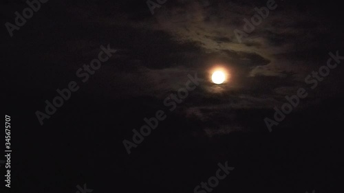 Night shooting of the moon on a dark sky. Passing clouds close the moon