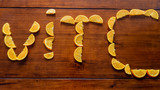Chopped orange on a wooden table. These pieces of orange form the letters Vit (vitamin) and the letter C.