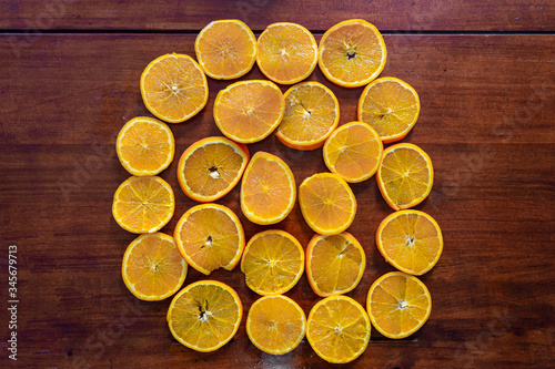 Chopped orange on a wooden table. These orange pieces are piled in the center of the table.