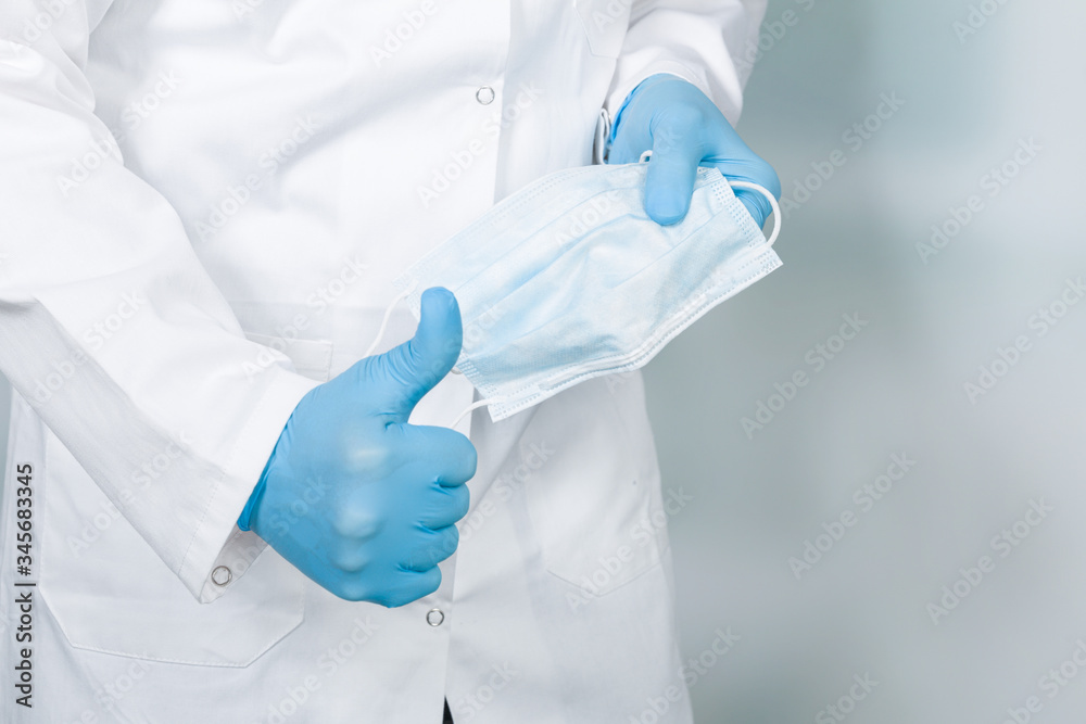 close up of doctor's hand with a medical face mask for virus protection showing thumbs up close up of doctor's hand with a medical face mask for virus protection showing thumbs up