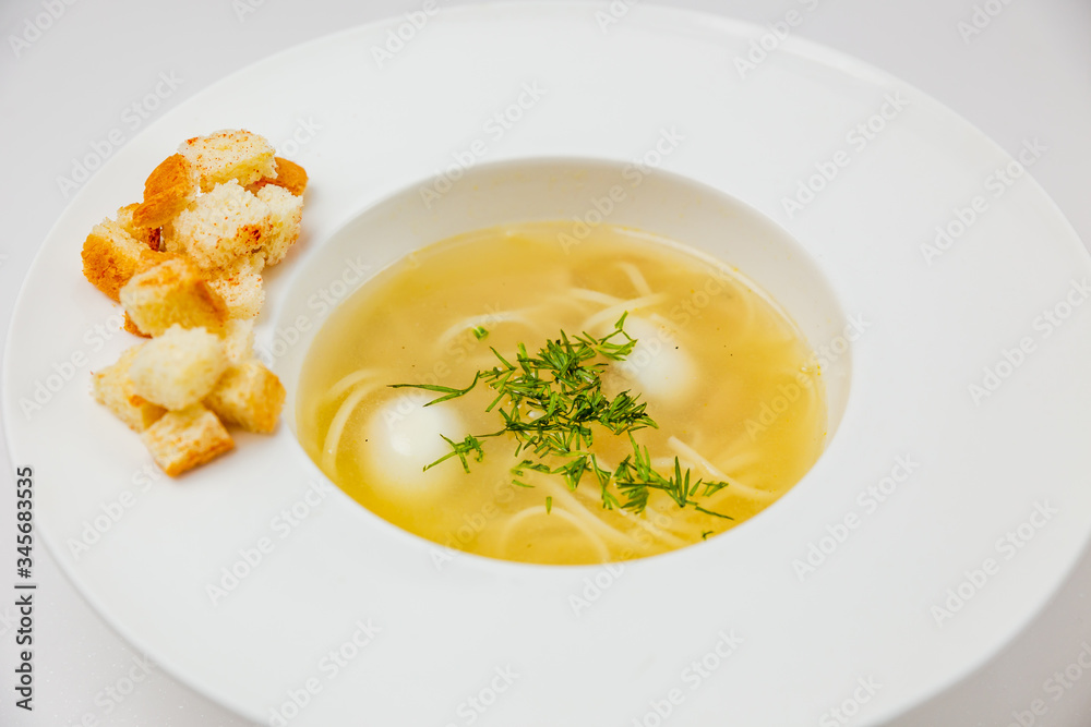A white plate of soup with noodles, quail eggs and croutons A white plate of soup with noodles, quail eggs and croutons