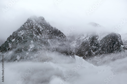 Mountain silhouette fragments through fog and clouds photo