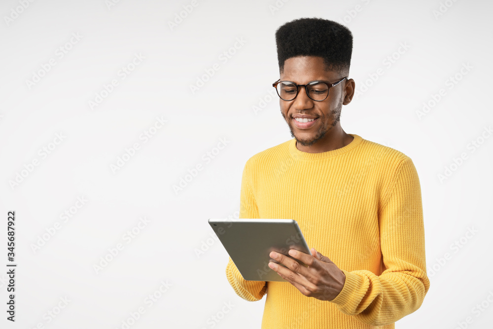 Smiling african guy using tablet digital isolated on white studio background Smiling african guy using tablet digital isolated on white studio background