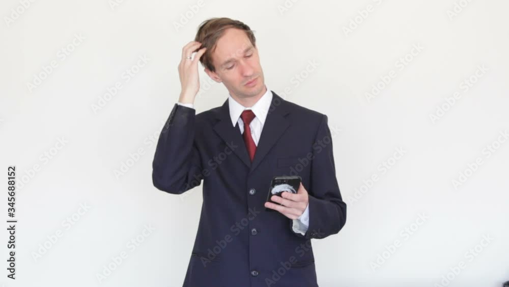Successful Businessman Looking At The Phone Screen and corrects hairstyle Successful Businessman Looking At The Phone Screen and corrects hairstyle
