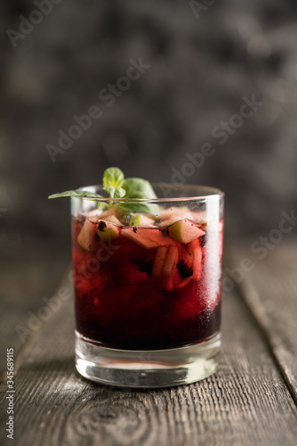 Old fashioned cocktail with blackberry liqueur and apple slices on rustic background. Selective focus. Shallow depth of field.