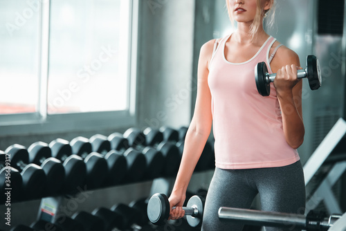 Beautiful Caucasian Sport Woman Lifting Dumbbells and Workout Exercises in Gym - Lifestyle and Healthcare Concept photo