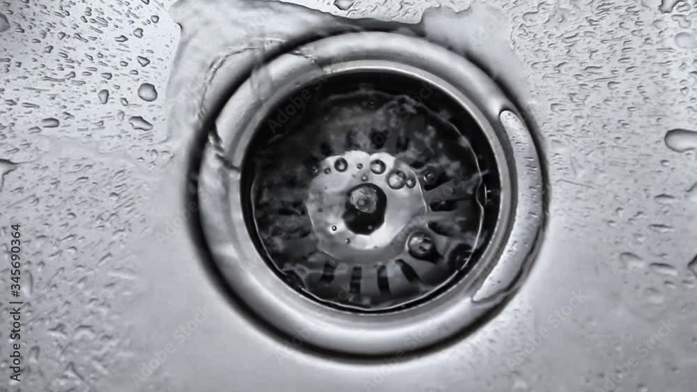 Water stream going down the drain. Streaming water in sink. Water dripping in stainless steel kitchen sink. Top view, flat lay Water stream going down the drain. Streaming water in sink. Water dripping in stainless steel kitchen sink. Top view, flat lay