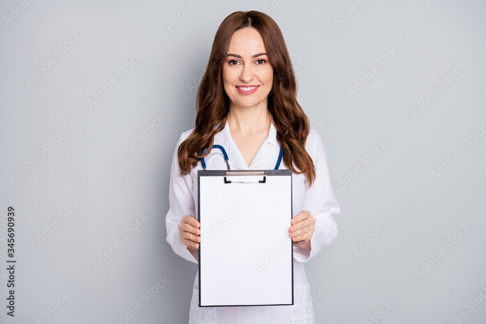 Portrait of nice attractive cheerful wavy-haired doc phonendoscope stethoscope demonstrating blank copyspace document sign clinic assistance isolated over grey pastel color background Portrait of nice attractive cheerful wavy-haired doc phonendoscope stethoscope demonstrating blank copyspace document sign clinic assistance isolated over grey pastel color background