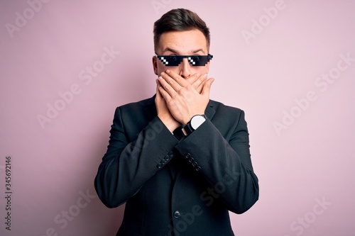 Young handsome caucasian business man wearing funny thug life glasses shocked covering mouth with hands for mistake. Secret concept.