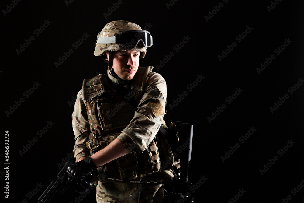 Fototapeta premium Soldier with gun is on mission on black background. Concept of war.